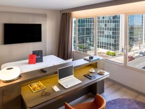 a hotel room with a desk with a laptop and a window at Novotel Campo De Las Naciones in Madrid