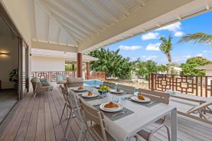 a dining table on the deck of a house at Villa Jamzmyn 45, Relaxen met prive plunge pool in Blue Bay