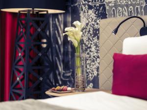 a vase with flowers on a table with a plate of food at Mercure Budapest Castle Hill in Budapest