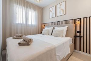 Un dormitorio con una gran cama blanca con toallas. en Sea View Apartment Estepona - Célere Sea Views, en Estepona 12 fotos más