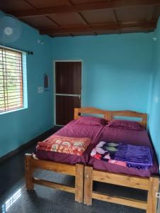 a bedroom with a wooden bed with purple sheets at Gubbikanta Homestay in Aralagodu