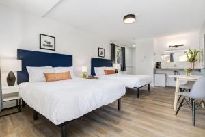 two beds in a room with a desk and a kitchen at Gateway Suites Lovely views near Banff in Canmore