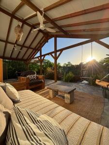 a patio with a bed and a table and the sunset at Lodge Kara in Grand-Bourg