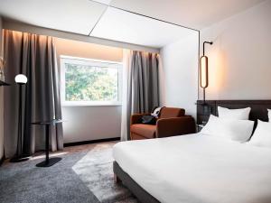 a hotel room with a bed and a chair at Novotel Belfort Centre Atria in Belfort +128 photos