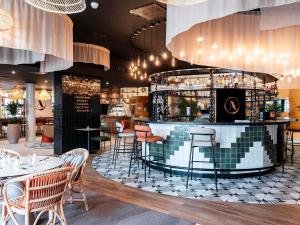 a restaurant with a bar with chairs and tables at Novotel Belfort Centre Atria in Belfort