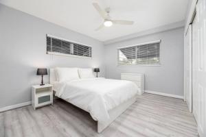a white bedroom with a bed and two windows at The Residences at Lake Ridge Apt 1 in Fort Lauderdale
