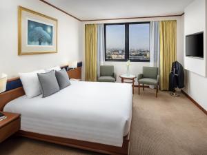Cette chambre comprend un grand lit blanc et des fenêtres. dans l'établissement Novotel Bangkok Bangna, à Bangna
