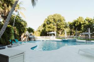 a swimming pool with chairs and umbrellas in a resort at Sprawling Bayfront Estate in Heart of Islamorada with Dockage, Beach, Pool, Kayaks, Bikes and More! in Islamorada +34 photos