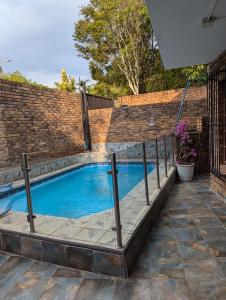 プレトリアにあるHome in Pretoria near Menlyn Maineのレンガ造りの壁の前のスイミングプール
