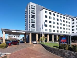 a large white building with cars parked in front of it at Novotel Rotorua Lakeside in Rotorua