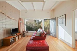 un soggiorno con un divano rosso e una TV di Honeysuckle Beach Haven a Cowes