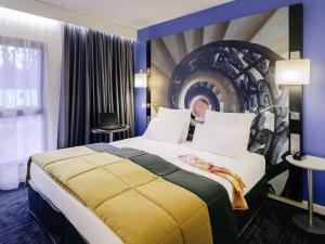 a hotel room with a large bed with a painting on the wall at Hotel De Bourbon Grand Hotel Mercure Bourges in Bourges