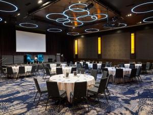 a conference room with tables and chairs and a projection screen at Sofitel Melbourne On Collins in Melbourne