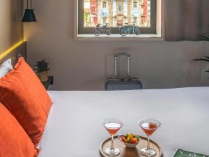 two glasses of wine and a bowl of fruit on a table at Mercure Porto Centro Santa Catarina in Porto