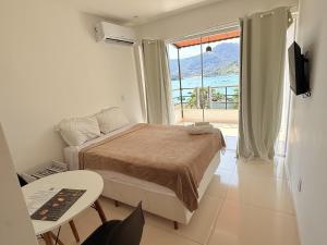 a bedroom with a bed and a table and a window at Apartamentos com vista para o Mar - Mirante do Marinas in Angra dos Reis