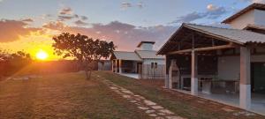 a house with the sunset in the background at Vila Arcanjo in Santana do Riacho