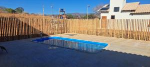 a blue swimming pool in front of a wooden fence at Vila Arcanjo in Santana do Riacho