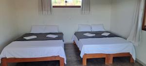two twin beds in a room with a window at Vila Arcanjo in Santana do Riacho