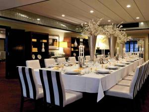 Una mesa larga con mesas blancas y sillas blancas. en Hotel St Moritz, Queenstown - MGallery Collection, en Queenstown
