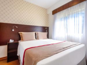 サンパウロにあるMercure Sao Paulo JKの大きなベッドと窓のある寝室