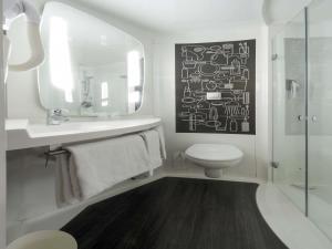 a bathroom with a sink and a toilet and a mirror at ibis London Docklands Canary Wharf in London