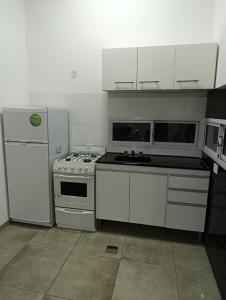 a kitchen with white cabinets and a stove and refrigerator at Sinaí Apart in Santa Rosa de Calamuchita