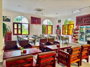 a restaurant with tables and chairs and windows at Piseth Private Villa Hotel in Battambang