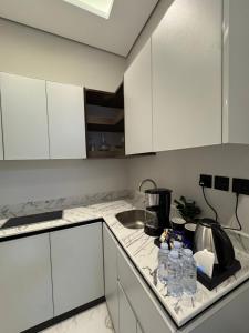 a kitchen with white cabinets and water bottles on the counter at غرفة ببانيو مع صالة 9 من أرام ريزدنس by ARAM Residence in Aţ Ţuwayr +5 photos