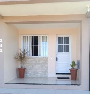 a front door of a house with two potted plants at Apart hotel - 2 tranquilidade e conforto de casa in Tuparendi