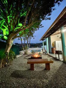 a fire pit with a bench in front of a house at Chácara do Paulinho in São Roque