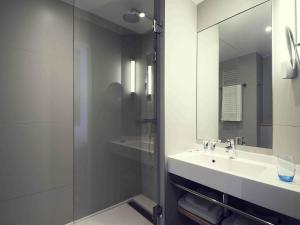 a bathroom with a sink and a shower with a mirror at Mercure Deauville Centre in Deauville +28 photos