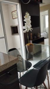 a glass table with chairs and a vase with white flowers at Aconchego in Porto Belo