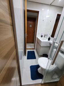 Un baño con inodoro, lavabo y espejo. en Apartamento confortável com ar condicionado, en Montes Claros