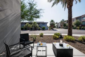 a patio with two chairs and a table and palm trees at Coach House - Hot Tub - Heart of Old Town in Scottsdale