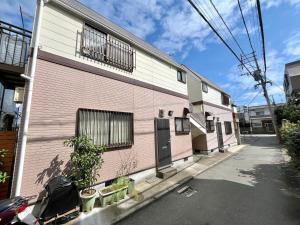 un bâtiment rose et blanc avec des plantes à côté dans l'établissement リトリートコートpaypayドーム, à Fukuoka