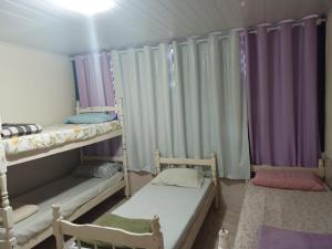 two bunk beds in a room with purple curtains at Pousada costa in Paraty