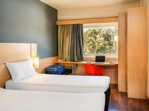 Una habitación de hotel con dos camas y un escritorio con una computadora portátil. en ibis Paulinia, en Paulínia