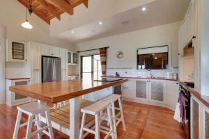 a kitchen with a wooden counter top and white cabinets at Chalet Tasmania in Judbury
