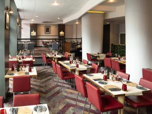 a restaurant with wooden tables and red chairs at Novotel Glasgow Centre in Glasgow