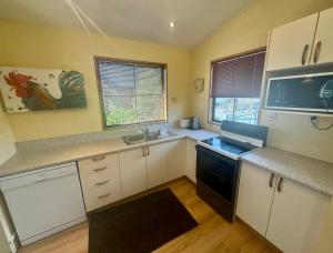 cocina con armarios blancos y fogones negros en 30 St James Avenue, en Hanmer Springs