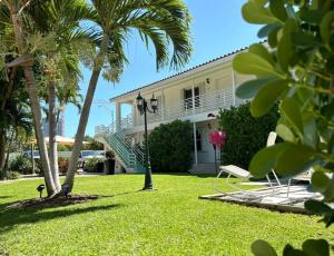 a white house with palm trees and a lawn at The Oasis in Miami