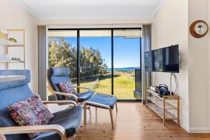 sala de estar con 2 sillas y ventana grande en Sandy Place Beach House managed by Batemans Bay Accom, en Long Beach