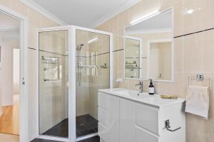 Un baño blanco con ducha y lavabo. en Sandy Place Beach House managed by Batemans Bay Accom, en Long Beach 21 fotos más