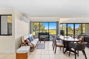 una sala de estar con un sofá, una mesa y sillas en Sandy Place Beach House managed by Batemans Bay Accom, en Long Beach