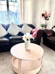 a living room with a couch and a table with flowers at Spacious main floor suite in Detached Bungalow with Parking & Kitchen in Calgary