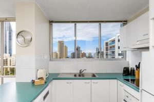 eine Küche mit weißen Schränken und einem großen Fenster in der Unterkunft Panorama in Gold Coast