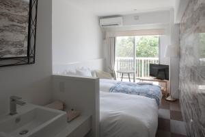a bedroom with a bed and a sink and a window at WITH SEA Nakama in Onna +4 photos