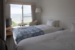a hotel room with two beds and a balcony at WITH SEA Nakama in Onna