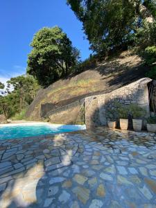 a swimming pool with a stone wall and water at Casa Principal in Itapeva
