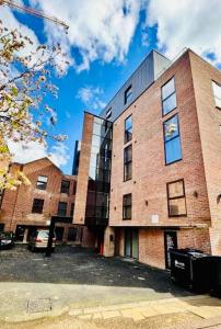 un edificio de ladrillo con un coche aparcado delante de él en Royal Stay-Leeds City centre Apartment, en Central Station